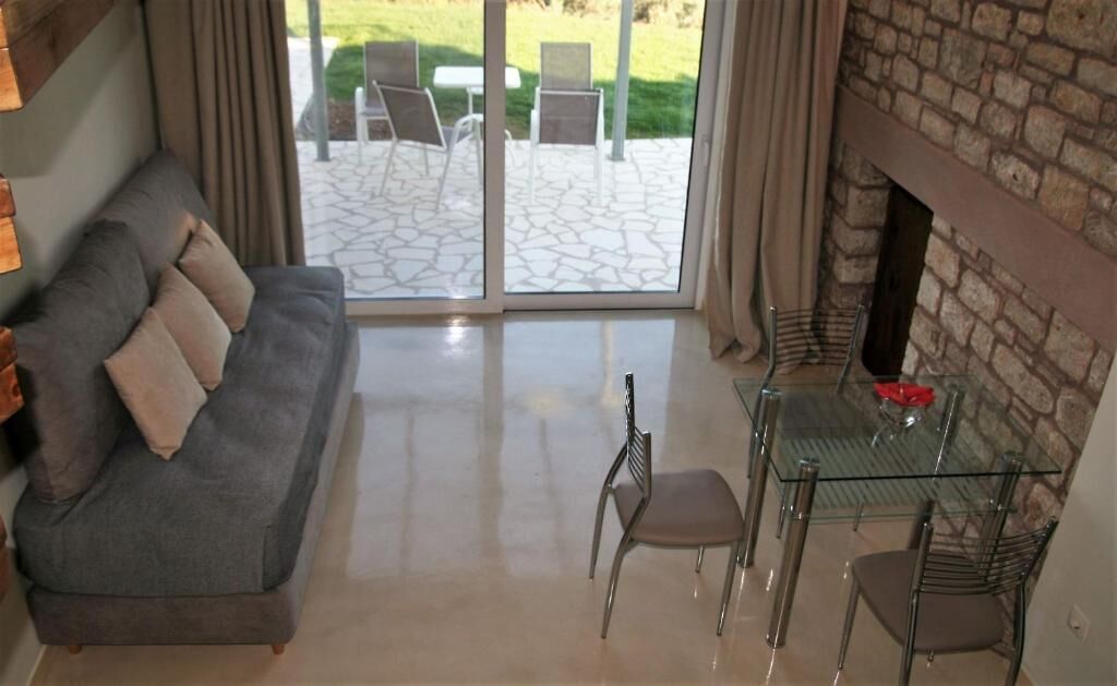 Een woonkamer met een bank, een glazen tafel en stoelen, een open haard, en een patio met stoelen en een tafel.