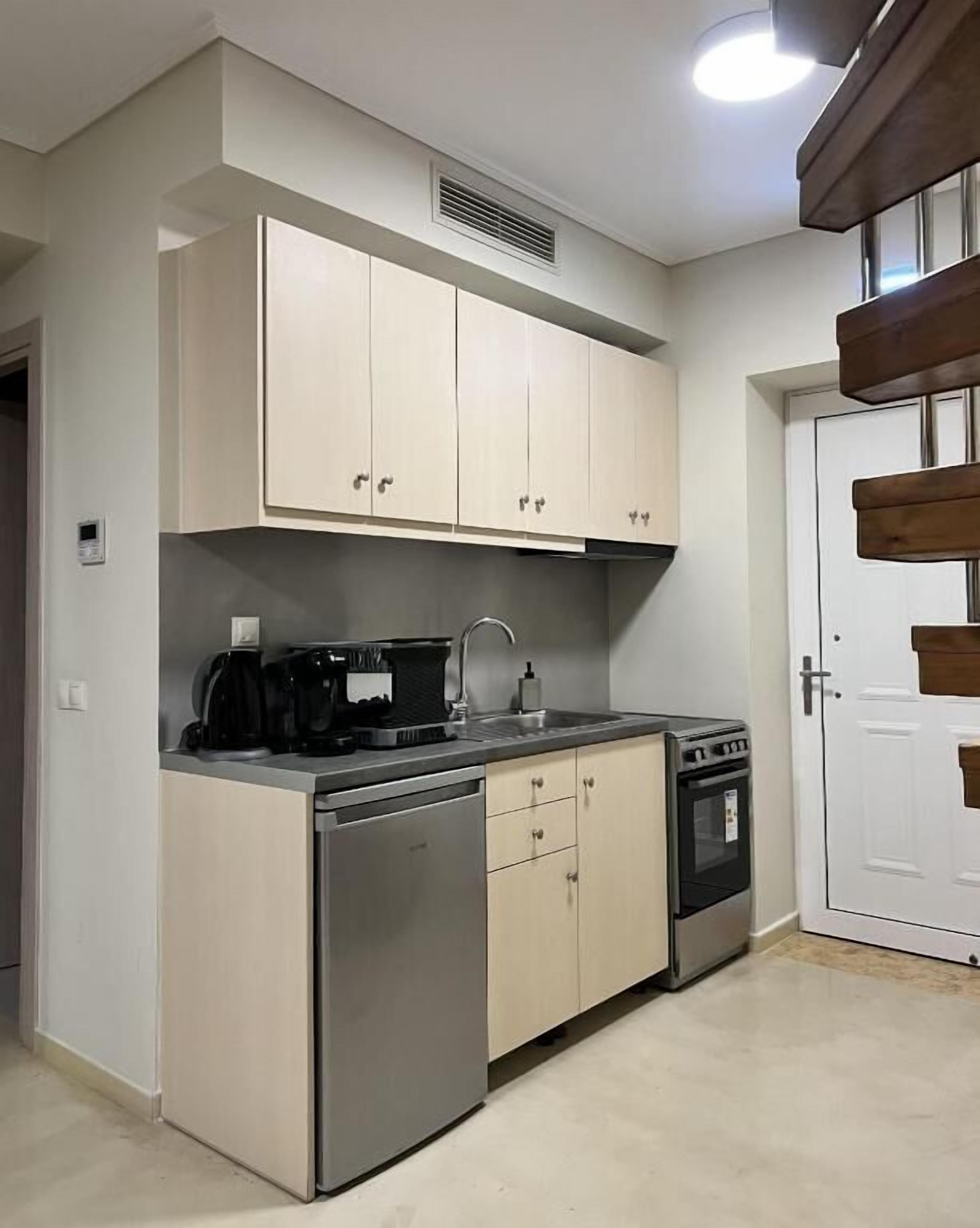 A compact kitchen with a dishwasher, stove, and a coffee maker.