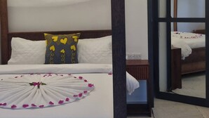 Een net opgemaakt bed met een decoratief kussen, een nachtkastje en een spiegel.