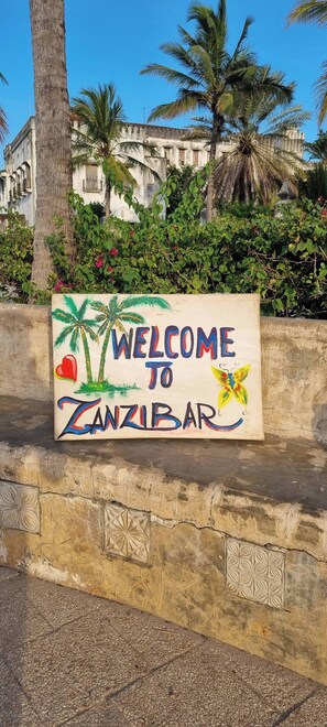A welcome sign to Zanzibar with palm trees and a butterfly. - Terry's villa pool view room (Unguja North Region)