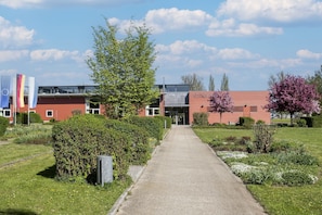 Ein Weg, der zu einem Gebäude mit roter Fassade und einer Flagge der Europäischen Union führt.