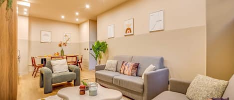 A modern living room with a grey sofa, a coffee table, and a dining area with a table and chairs.
