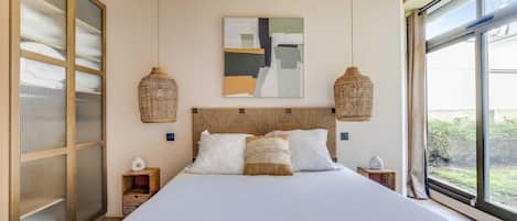 Een slaapkamer met een groot bed, twee nachtkastjes, een wanddecoratie in abstracte stijl en een groot raam met uitzicht.