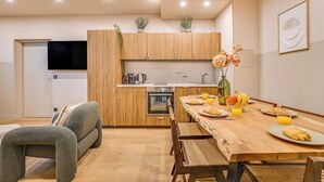 A modern kitchen with wooden cabinets, a dining table set with plates, glasses, and a vase of flowers. - Spacious Apartment - 2BR/10P - Place d'Italie (Paris)