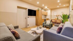 A modern living room with a grey sofa, a coffee table, and a dining area with a table and chairs. - Spacious Apartment - 2BR/10P - Place d'Italie (Paris)