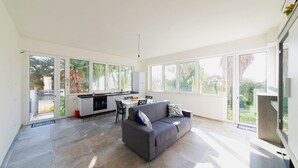 A spacious living area with a grey sofa, a dining table, and a kitchen area. - Holiday Home in 	Mazara del Vallo (Mazara del Vallo (TP))