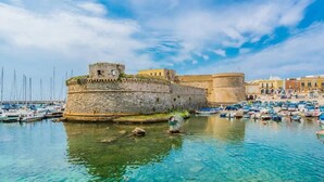 A coastal town with a historic stone fortification, clear blue waters, and a marina with numerous boats. - Apartment in Torre Suda, Racale (Torre Suda Provincia Lecce)