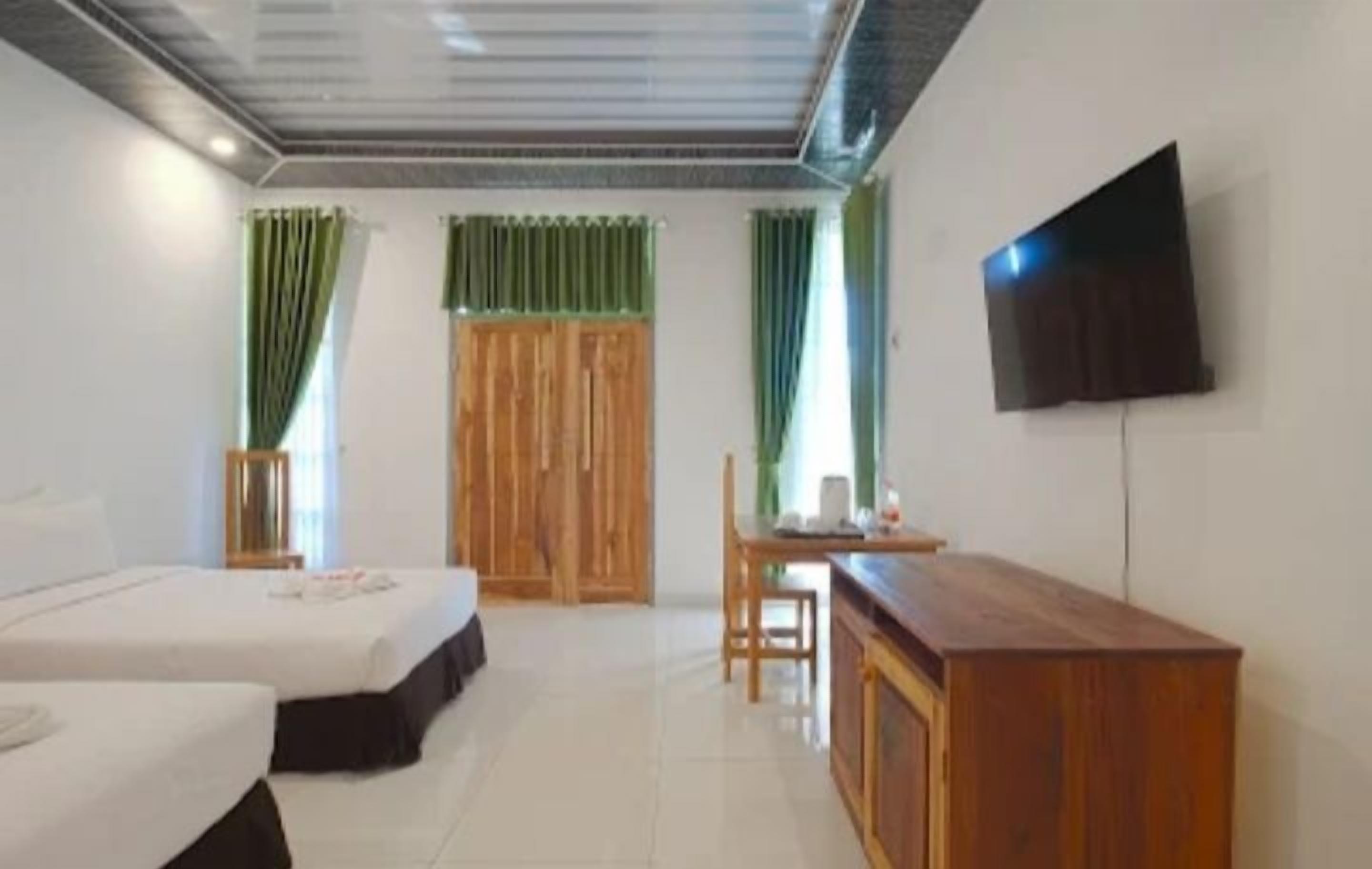 Een hotelkamer met een bed, een bureau, een stoel, een televisie en gordijnen.