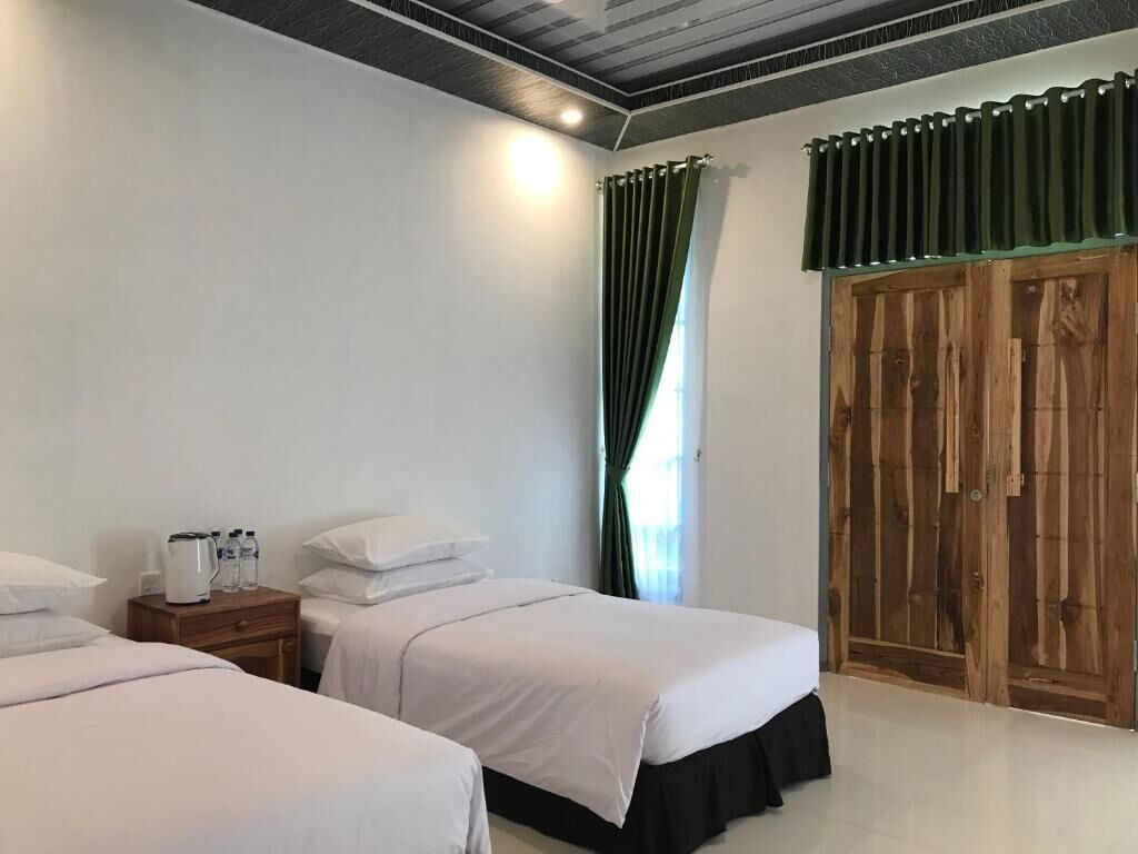 Une chambre d’hôtel avec deux lits, une armoire en bois et une table de chevet avec une bouilloire et des bouteilles.