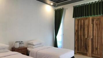 Une chambre d’hôtel avec deux lits, une armoire en bois et une table de chevet avec une bouilloire et des bouteilles.