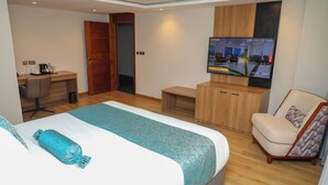 Ett hotellrum med en säng, ett skrivbord, en stol, en tv och en garderob.