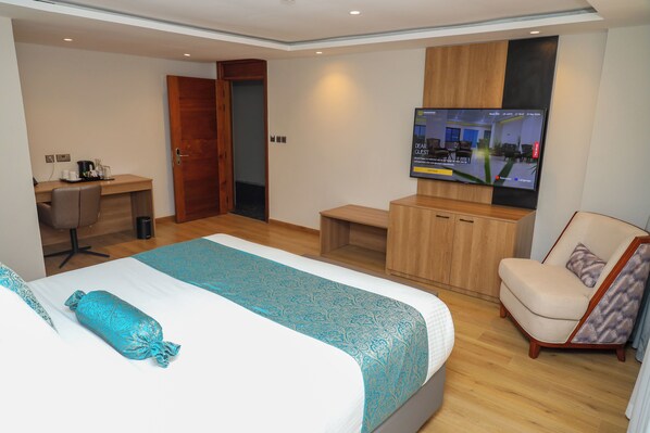 Una habitación de hotel con cama, escritorio, silla, televisión y armario.