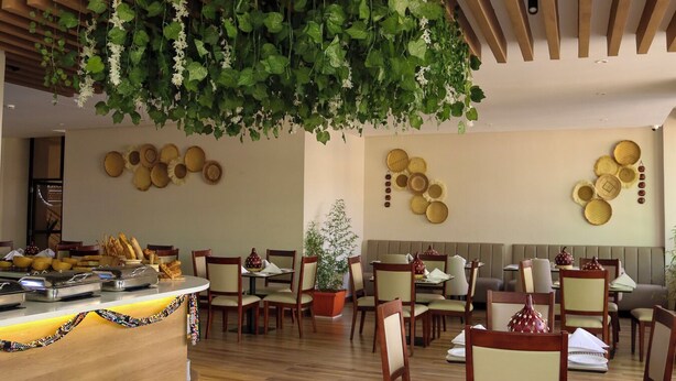 En restaurang med ett träpanelat tak, hängande växter och en vägg dekorerad med flätade korgar.