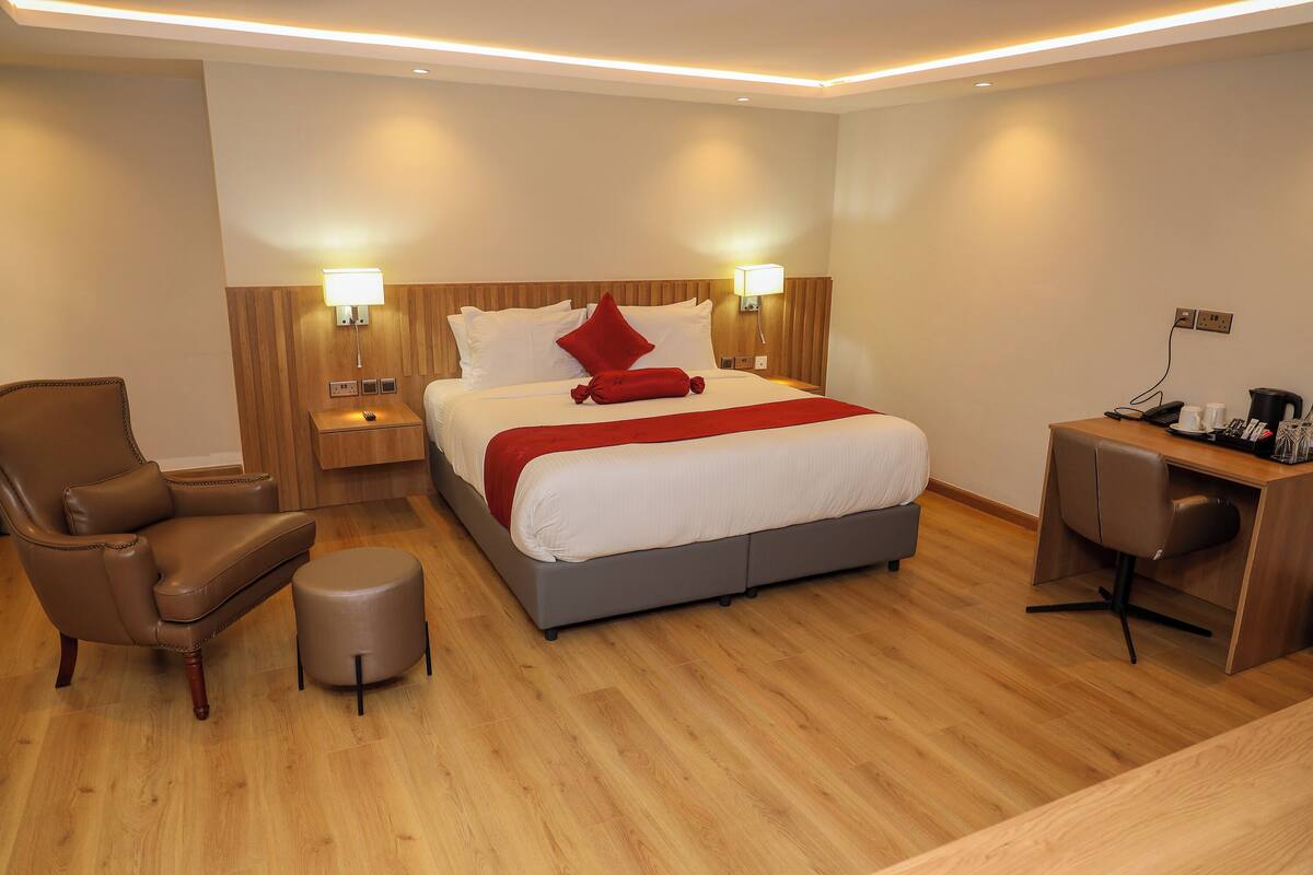 A hotel room with a bed, a chair, a desk, and a nightstand.