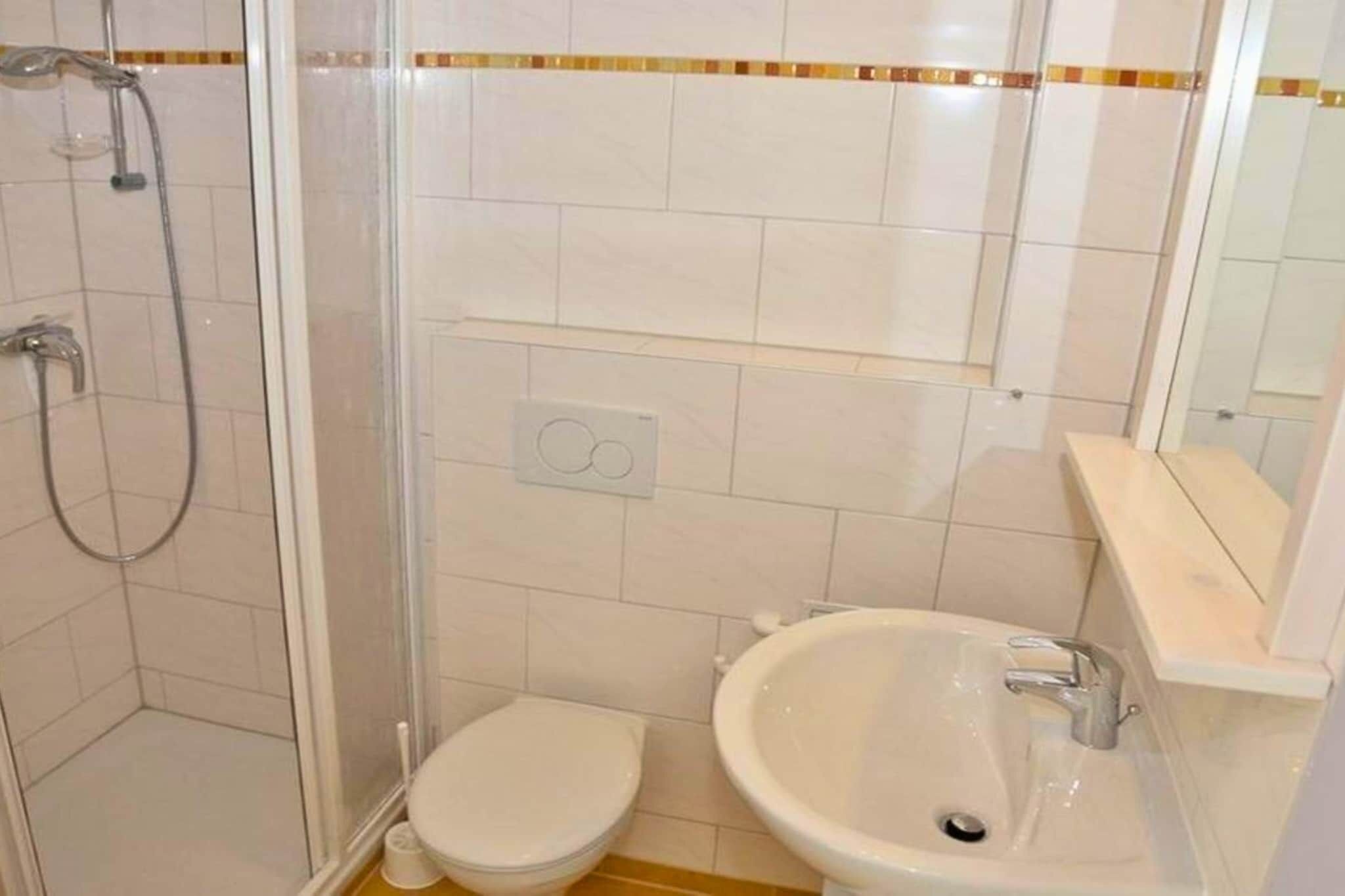 Une salle de bain avec une douche à parois de verre, des toilettes et un lavabo.