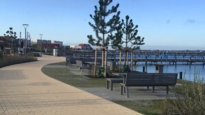 Un paseo marítimo con bancos, un sendero y un muelle que se adentra en el agua.
