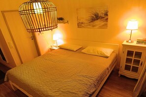 Une chambre à coucher comprenant un lit, des lampes de chevet, une table de chevet, une armoire et un luminaire suspendu.