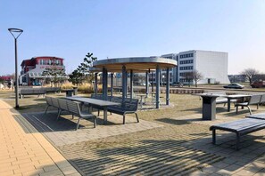Un espace public extérieur aménagé avec des bancs, des tables et un kiosque.