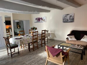 A dining area with a table set for six, surrounded by wooden chairs. There is a sofa with cushions and a coffee table with magazines. - *** Clos d'Éden renovated in 2026 between St-Malo and Rennes in a peaceful hamlet (Plesder)