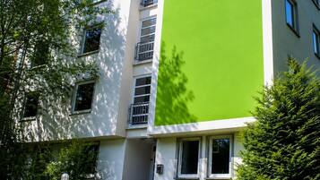 Un immeuble à plusieurs étages doté de balcons, de fenêtres et de verdure.