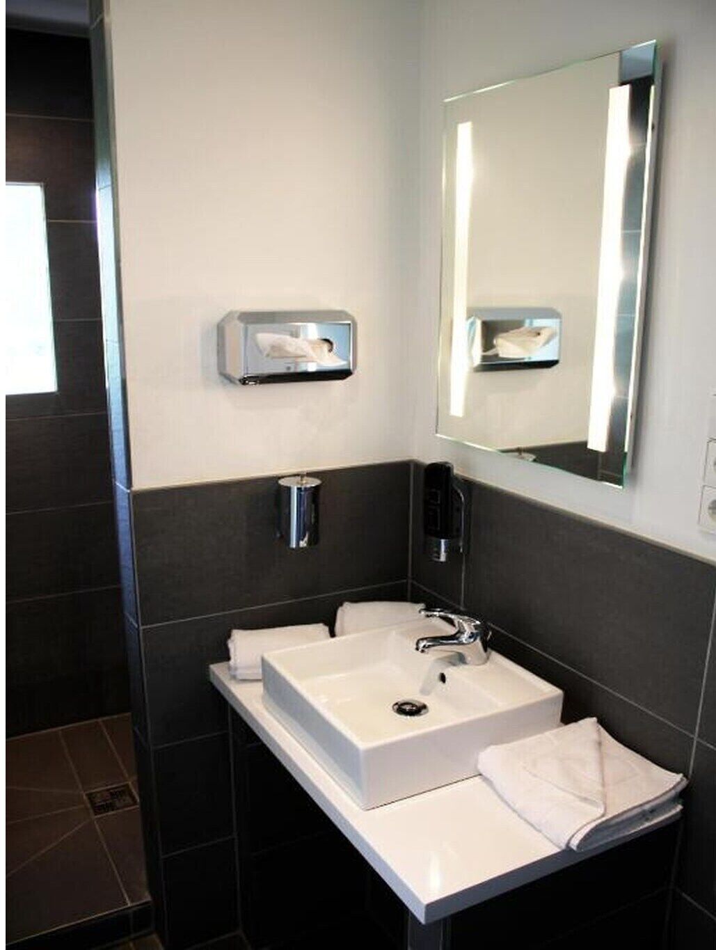 Un bagno moderno con due lavabi, uno specchio e un portasciugamani.