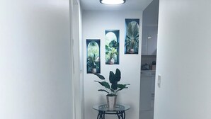 En hall med ett bord med glasskiva, krukväxter och en taklampa.