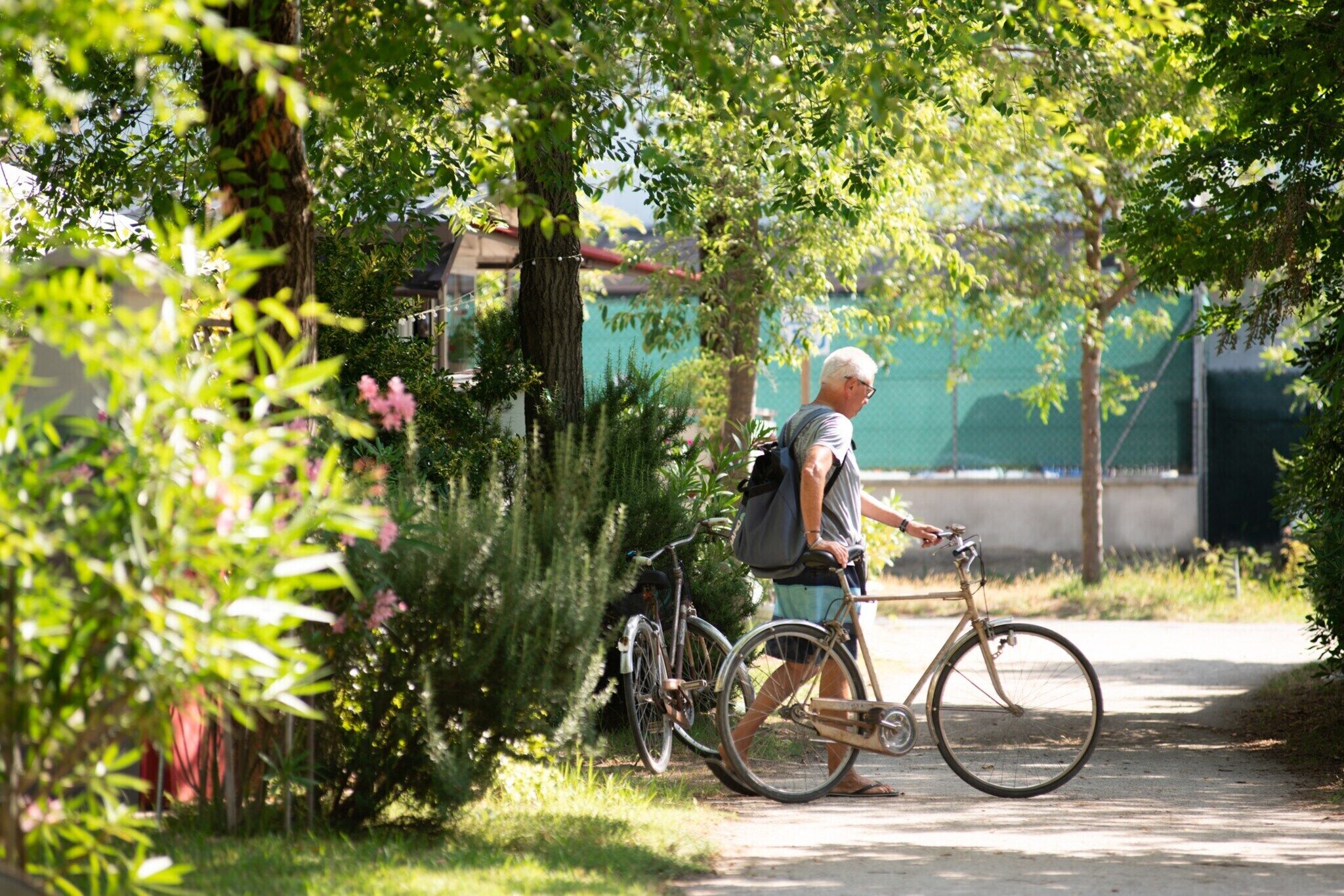 A person standing next to a bicycle on a path surrounded by greenery.