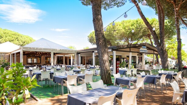 An outdoor dining area with tables and chairs, a covered seating area, and a view of a hill. - Cozy mobile home in Cesenatico (Cesenatico)