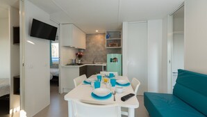 Ett kompakt bostadsutrymme med ett litet kök, en matplats och en soffa.