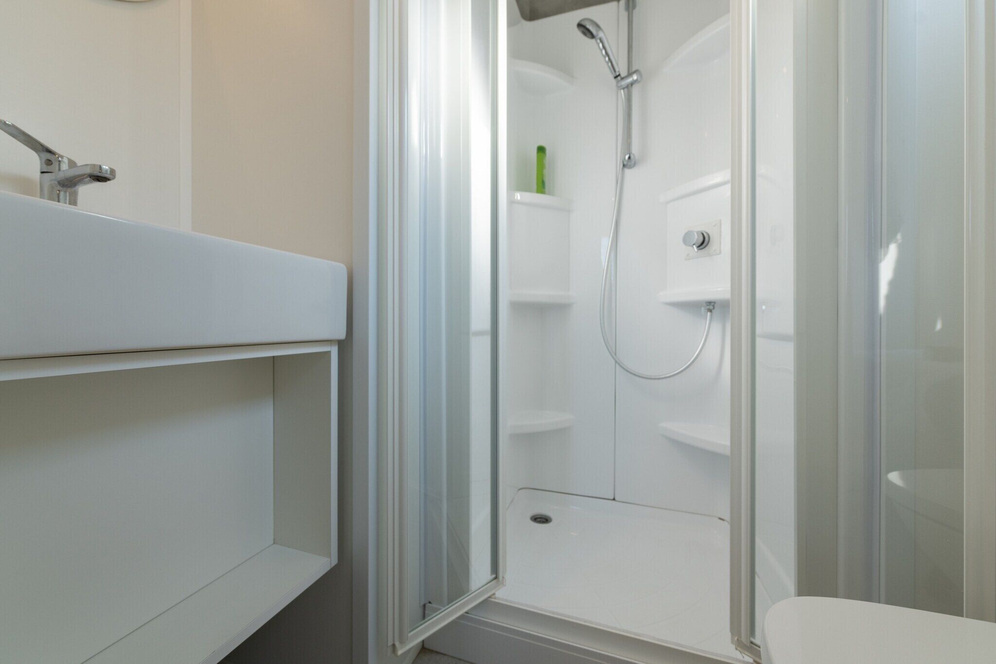 A modern bathroom with a glass-enclosed shower, a white sink, and a toilet.