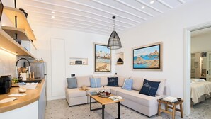 Una sala moderna con sofá, mesa de centro y una cocina con pileta y mostrador.