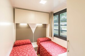A small, single-room accommodation with two beds, a window, and a ceiling light. - High-quality mobile home on Lake Garda (Toscolano - Maderno)