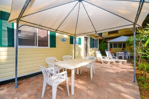 An outdoor patio with a table and chairs under a large umbrella, surrounded by greenery. - High-quality mobile home on Lake Garda (Toscolano - Maderno)