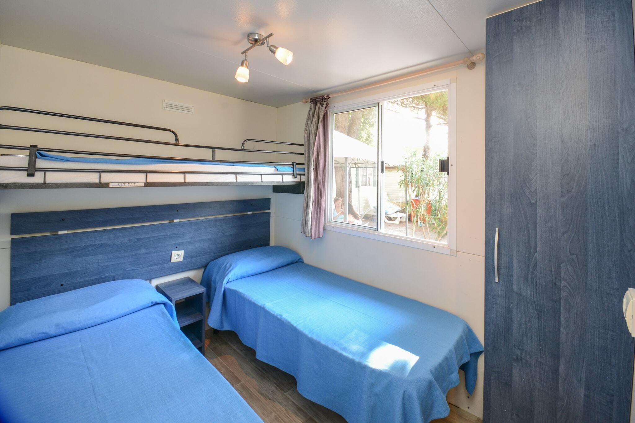 Une chambre avec des lits superposés, une fenêtre avec des rideaux et une armoire.