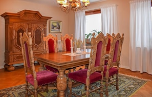 Une salle à manger avec une table en bois, des chaises décorées et un lustre.