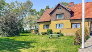 A two-story house with a red-tiled roof, a brick facade, and a well-maintained lawn with a picnic table. - 4 bedroom beautiful home in Glemmingebro (Glemmingebro)
