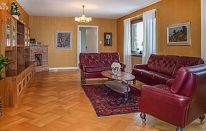 Un salon avec deux canapés en cuir rouge, une table basse en bois et un tapis à motifs.