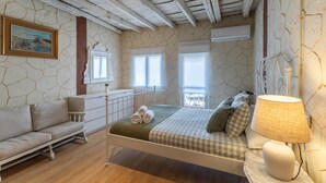 Ein Schlafzimmer mit einem Bett, einem Sofa, einer Lampe und einem Gemälde an der Wand.