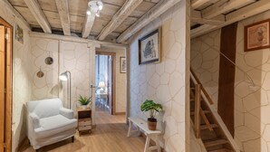 Ein Flur mit einem weißen Sofa, einer Sitzbank, einer Topfpflanze und einer Treppe.
