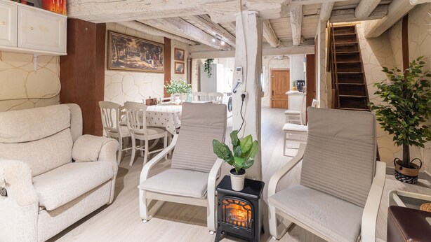 Ein gemütliches Wohnzimmer mit einer Couch, Sesseln, einem Kamin und einem Essbereich.