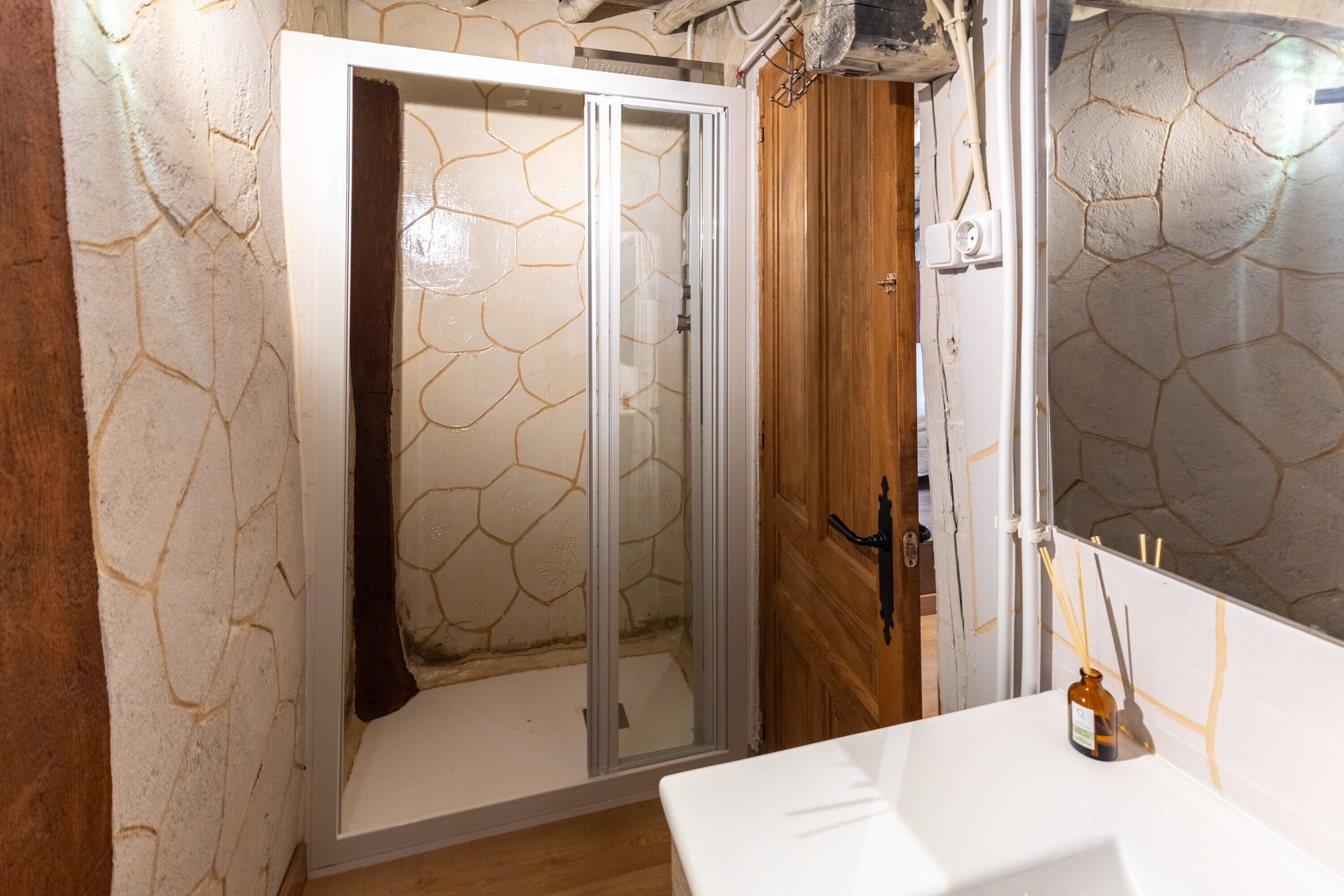 Une salle de bain avec une douche, un lavabo et une porte en bois.