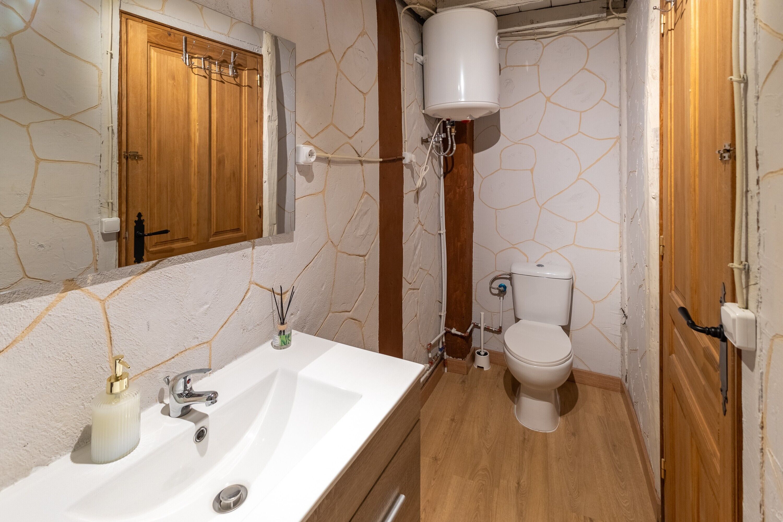 Une salle de bain avec un lavabo blanc, un meuble en bois et des toilettes.