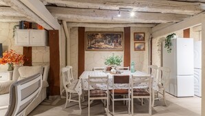 Ein Essbereich mit Tisch, Stühlen, einer Couch, einem Kühlschrank und einem Bild an der Wand.