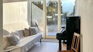 Una habitación con sofá, piano y vistas a través de un ventanal.