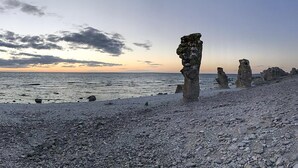 Un paisaje costero con formaciones rocosas y un mar tranquilo al atardecer.