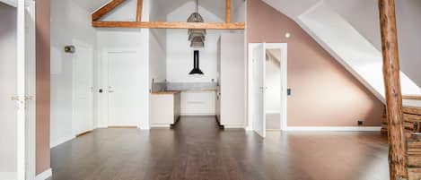 Un loft espacioso con vigas de madera a la vista, una zona de cocina y una escalera que conduce a un nivel superior.
