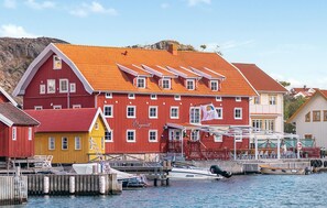 Un edificio rojo con adornos blancos en las ventanas y una puerta amarilla, amarrado a un muelle con barcos.