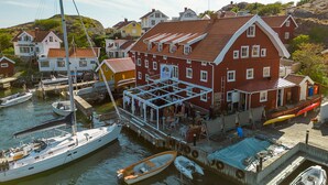 A waterfront building with a covered deck area, docked boats, and a hillside backdrop. - Awesome apartment in Kyrkesund with WiFi (Kyrkesund)
