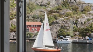 A sailboat with a white sail and the number 53288 on its mast, docked near a rocky shoreline with a red building in the background. - Awesome apartment in Kyrkesund with WiFi (Kyrkesund)