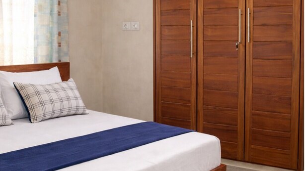 Ein Schlafzimmer mit einem hölzernen Bett, einer blauen Tagesdecke und einem großen Holzschrank.